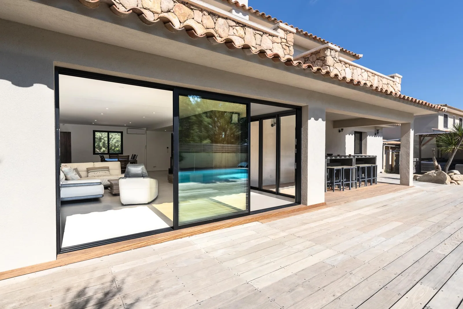 Villa contemporaine avec grande baie vitrée coulissante en aluminium ouvrant sur une terrasse et une piscine