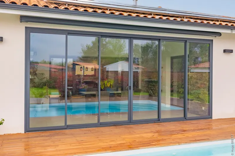 Baie coulissante aluminium FPEE Sensation 3 à six vantaux gris anthracite face à la piscine
