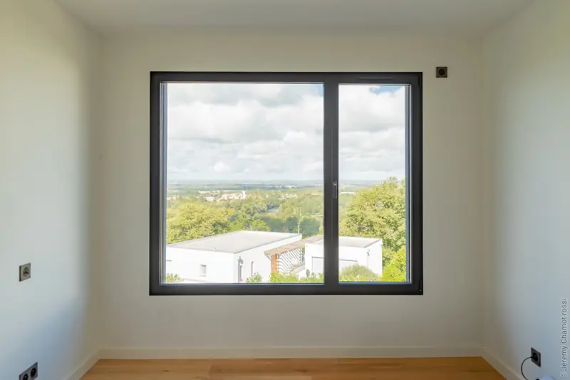 Fenêtre aluminium FPEE Sensation 2 noire à ouvrant caché, vue sur la campagne