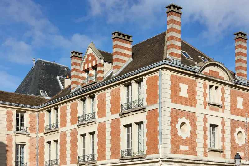 Fenêtres bois FPEE Hexagone gris clair sur un bâtiment historique en brique
