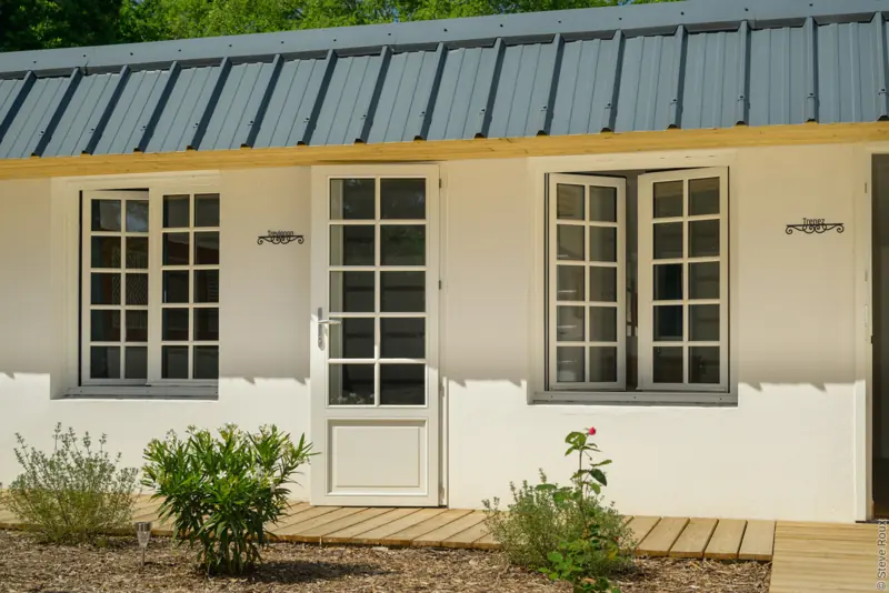 Fenêtres et porte-fenêtre bois FPEE Hexagone blanches à petits bois sur une façade de plain-pied
