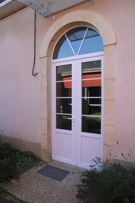Porte cintrée PVC FPEE Sérénité 70 avec imposte sur une façade claire