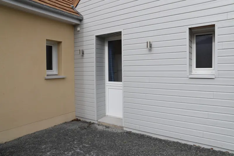 Porte d'entrée PVC FPEE Fermière blanche sur une façade bardée
