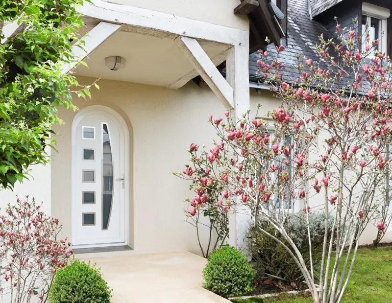 Porte d'entrée PVC FPEE Voile cintrée blanche sous un porche fleuri
