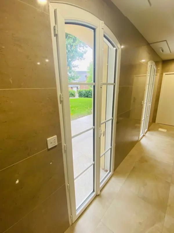 Porte-fenêtre PVC FPEE Sérénité 70 en arc surbaissé ouvrant sur le jardin