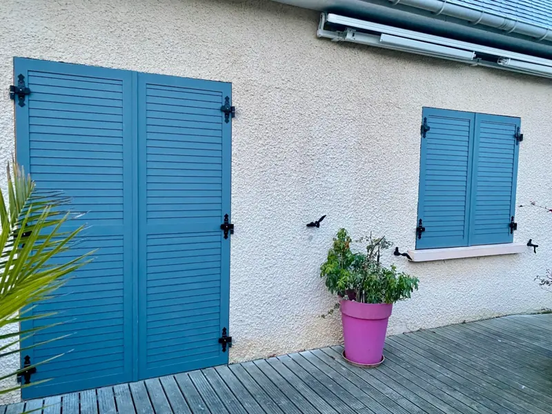 Volets battants aluminium FPEE Natalia gris bleu sur une terrasse